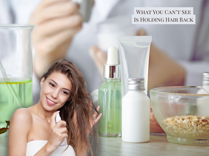 Smiling woman applying hair spray next to clean beauty products—emphasizing invisible causes of hair damage and benefits of clean, plant-based haircare.