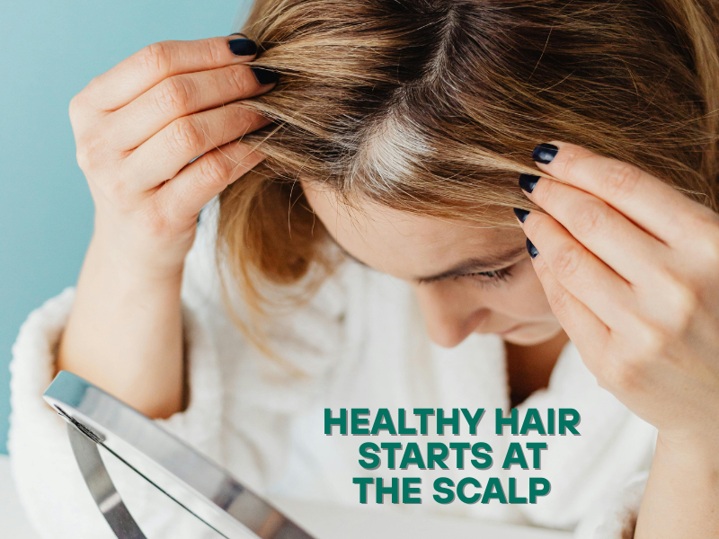 Woman closely examining her scalp in mirror—emphasizing the connection between scalp care and healthy hair growth.